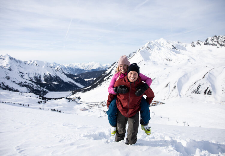 Mann trägt Frau Huckepack durch den Schnee